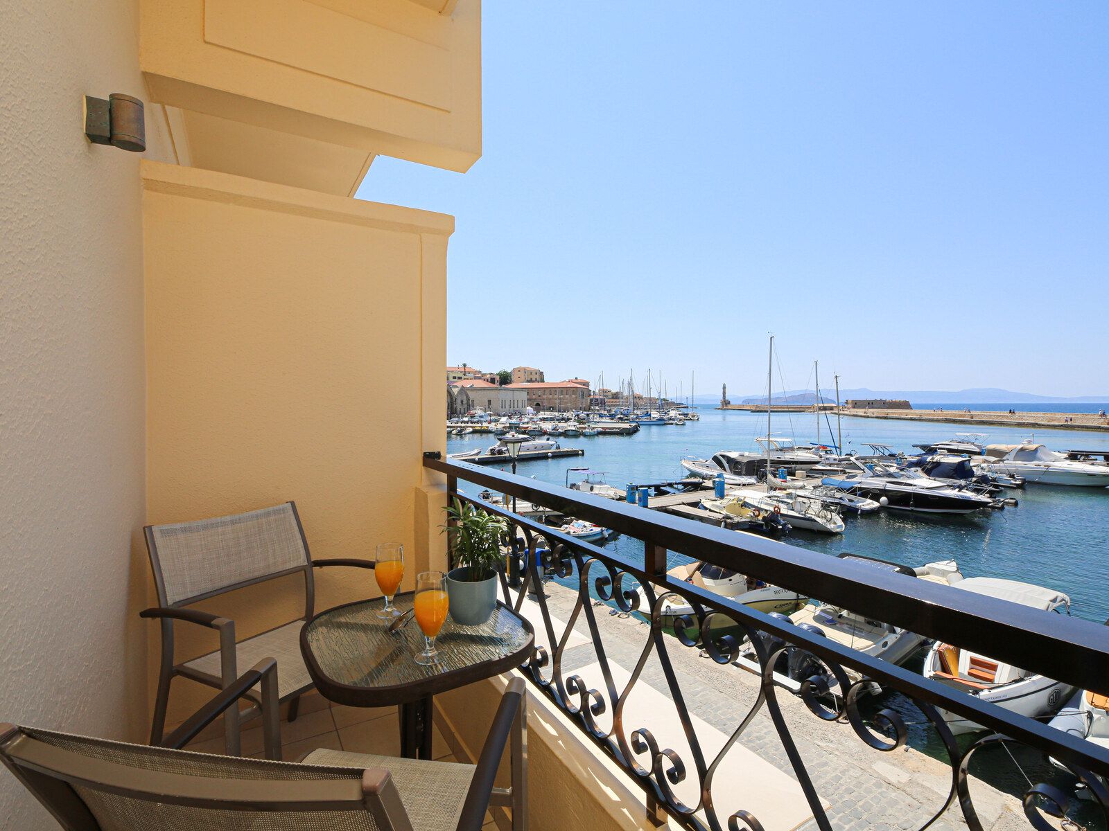 Ein Balkon mit Tisch und Stühlen mit Blick auf einen Yachthafen mit Booten und Gebäuden.
