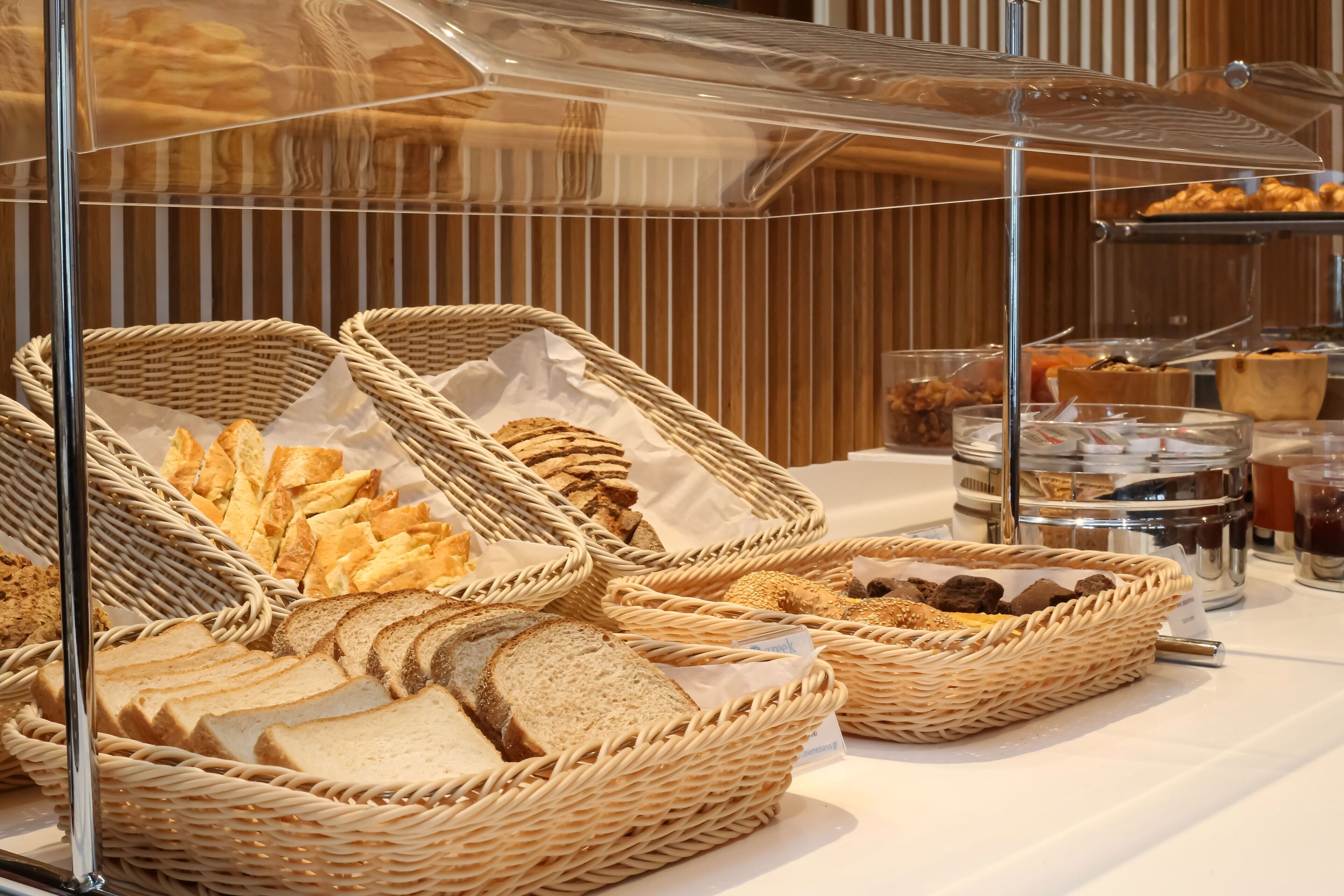 Een buffet met verschillende broden en gebak, gepresenteerd in rieten manden.
