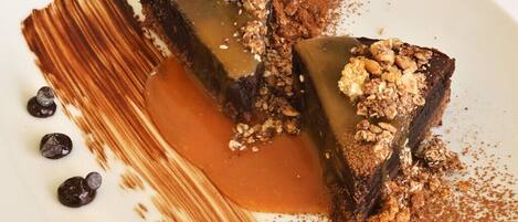 A dessert plate with a chocolate cake, caramel sauce, and granola topping.