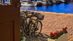 A view from a door to a harbor with boats, a lighthouse, and a bicycle. - Porto Veneziano Hotel (Chania)