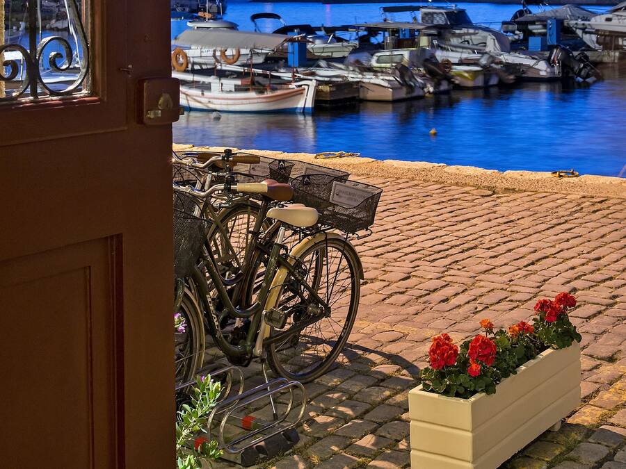 Vista desde una puerta hacia un puerto con barcos, un faro y una bicicleta.