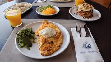 A table with plates of food, a glass of orange juice, and a napkin with a logo.