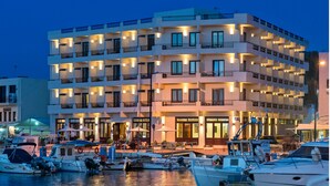 A multi-story hotel with balconies, a marina with boats, and outdoor seating areas. - Porto Veneziano Hotel (Chania)