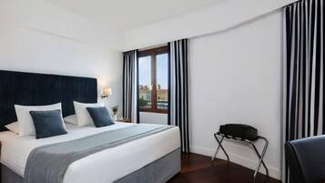 A hotel room with a large bed, a desk, and a chair.