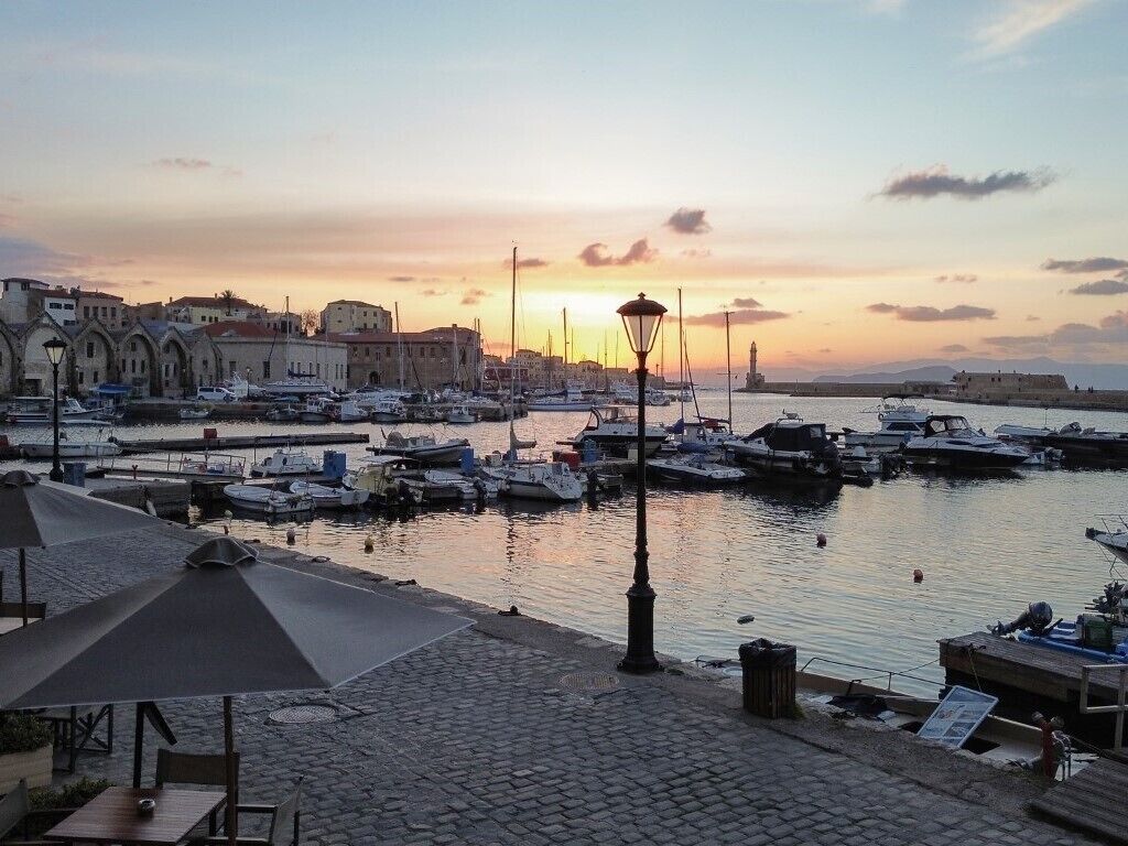 Un puerto deportivo con barcos amarrados, un muelle de adoquines y edificios al fondo.