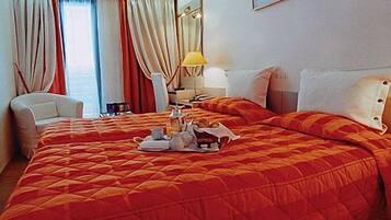 Une chambre d’hôtel avec un grand lit, une chaise, une table de chevet avec une lampe et un plateau de petit-déjeuner posé sur le lit.
