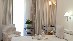 A hotel room with two beds, a chair, a small table with a tray of breakfast items, a desk with a lamp, and curtains. - The Park Hotel Piraeus (Piraeus)