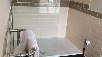 A modern bathroom with a glass-enclosed shower, a white toilet, and a black floor.