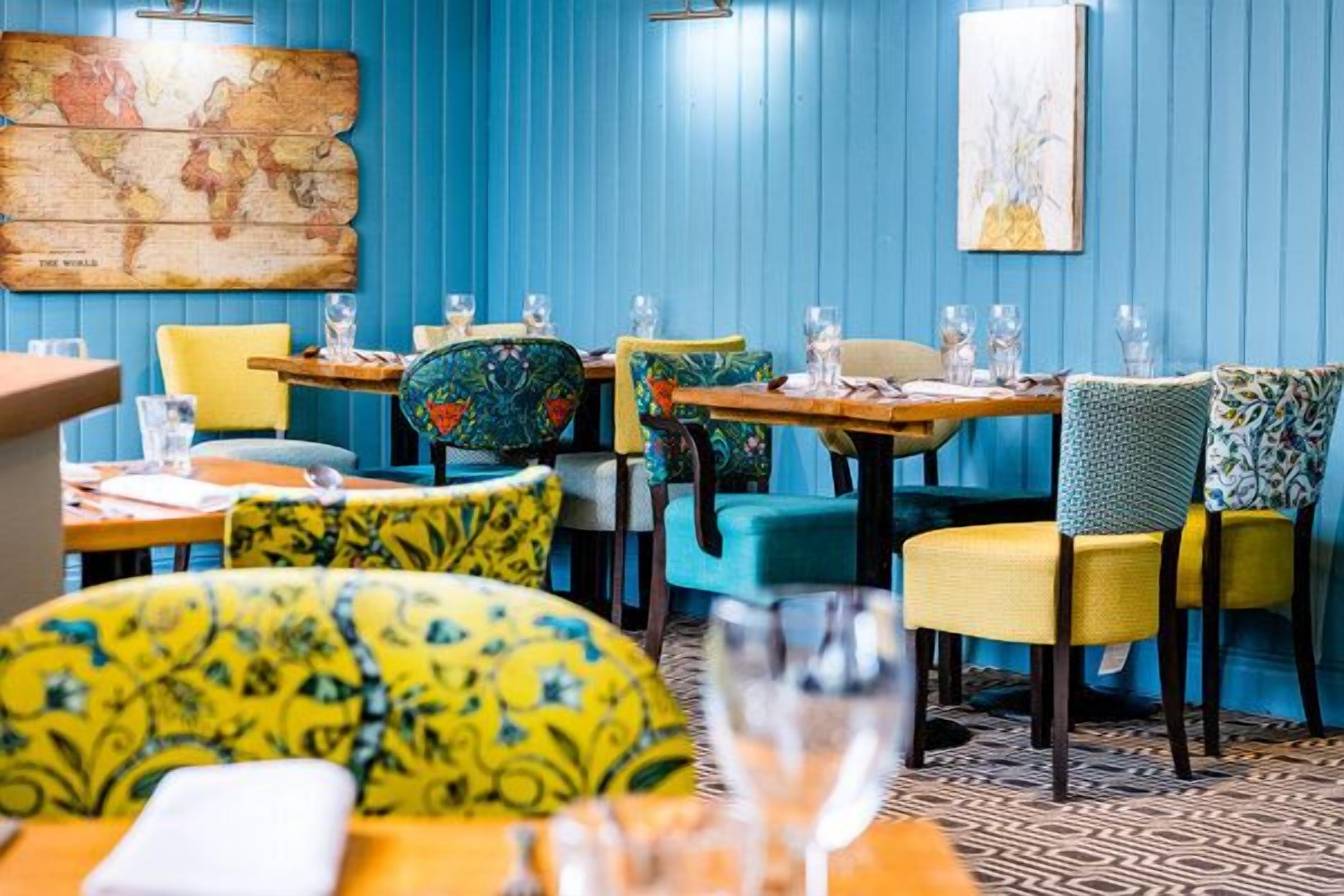 A restaurant interior with blue walls, colorful chairs, and a world map on the wall.