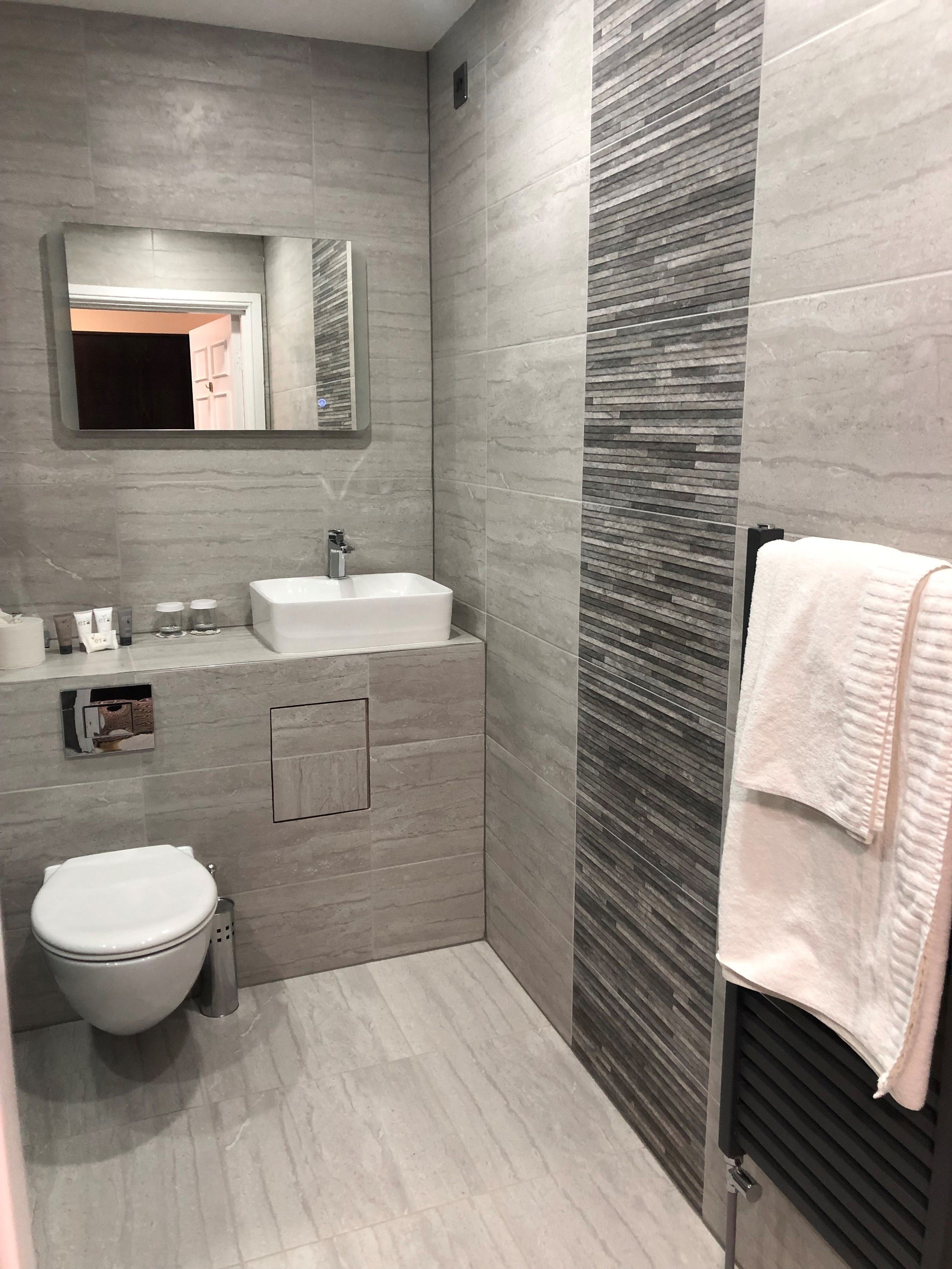 Een moderne badkamer met een wit wastafel, spiegel en toilet.