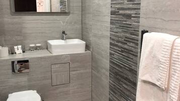 Een moderne badkamer met een wit wastafel, spiegel en toilet.