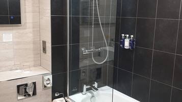 Une salle de bain moderne avec une douche à parois de verre, une baignoire blanche et des toilettes.