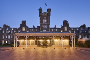 A grand hotel entrance with a prominent tower and a covered entrance area.