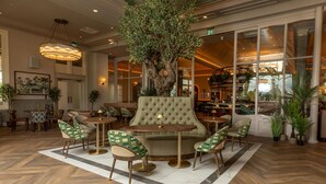 A lobby with a large tree, comfortable seating, and a view of the restaurant area.