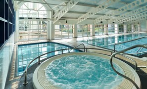 Relax by the pool with a hot tub at the center, surrounded by a spacious deck and large windows.