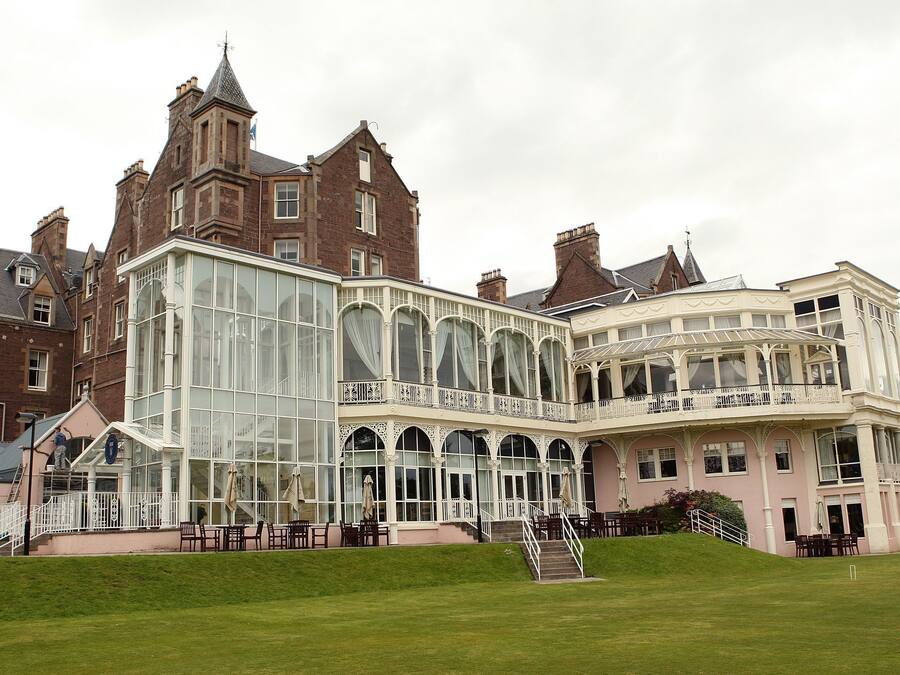 Un grand bâtiment historique doté d’une véranda en verre et d’une façade rose.