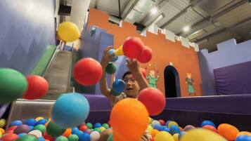 A child playing in a ball pit with colorful balls.