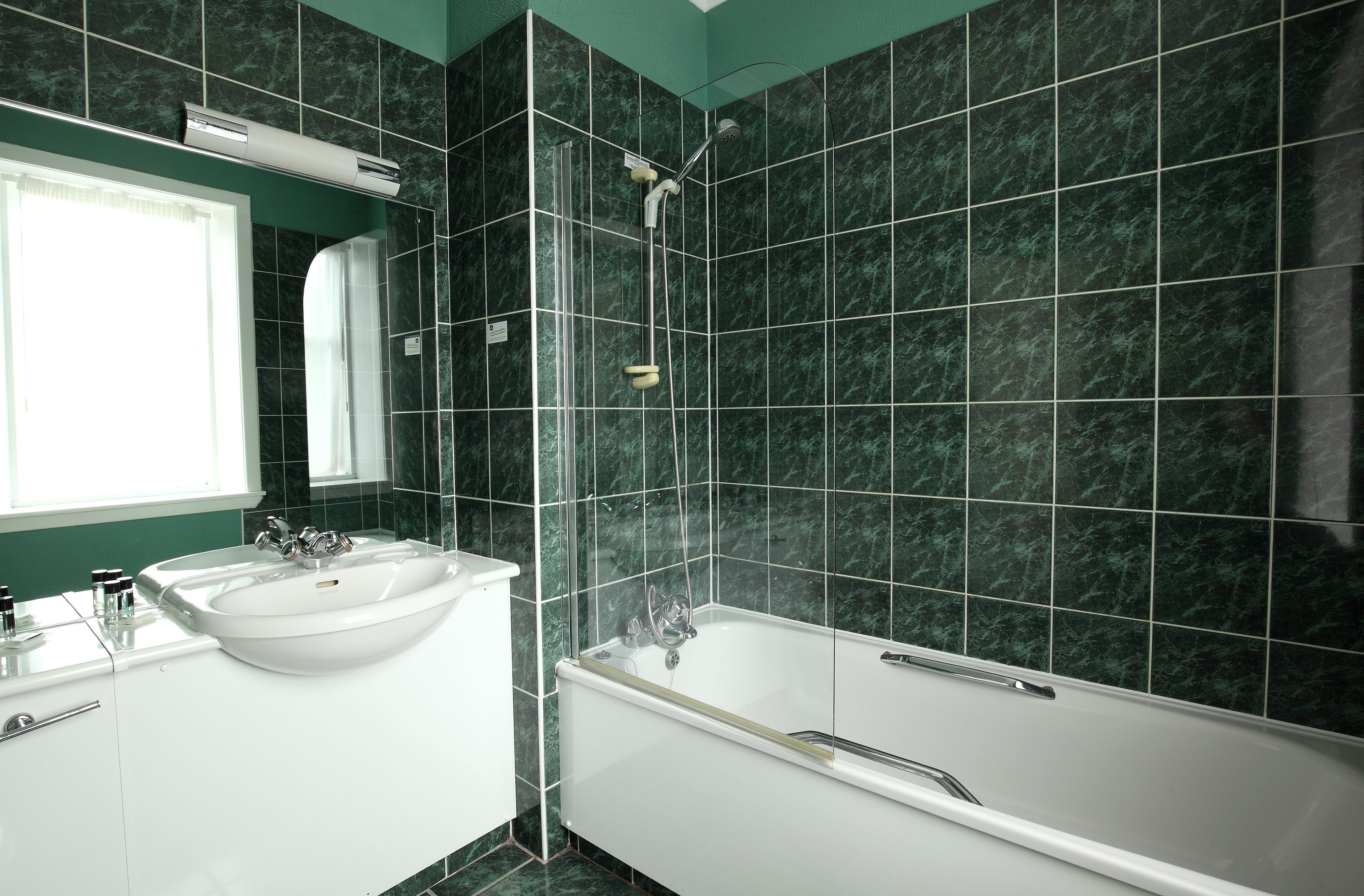 A bathroom with a white bathtub, two sinks, and a glass shower enclosure.