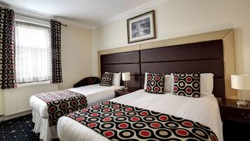 A hotel room with two beds, a large framed picture on the wall, and a window with curtains.