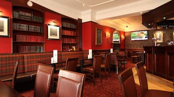 Een restaurant met rode wanden, houten boekenkasten en een bar.