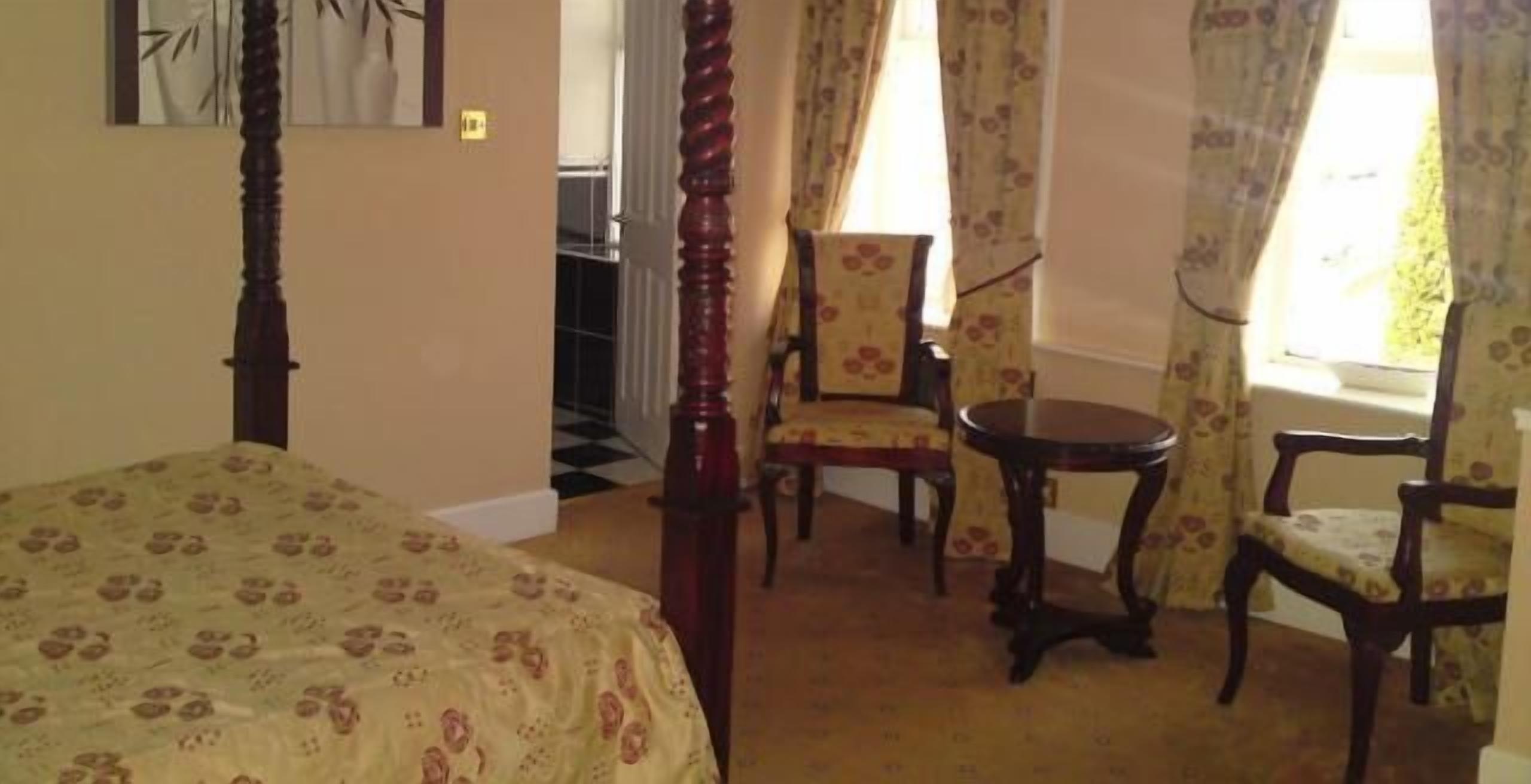 A bedroom with a bed, a chair, a table, and a window with curtains.