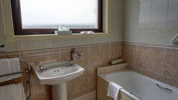 A bathroom with a sink, bathtub, and window.