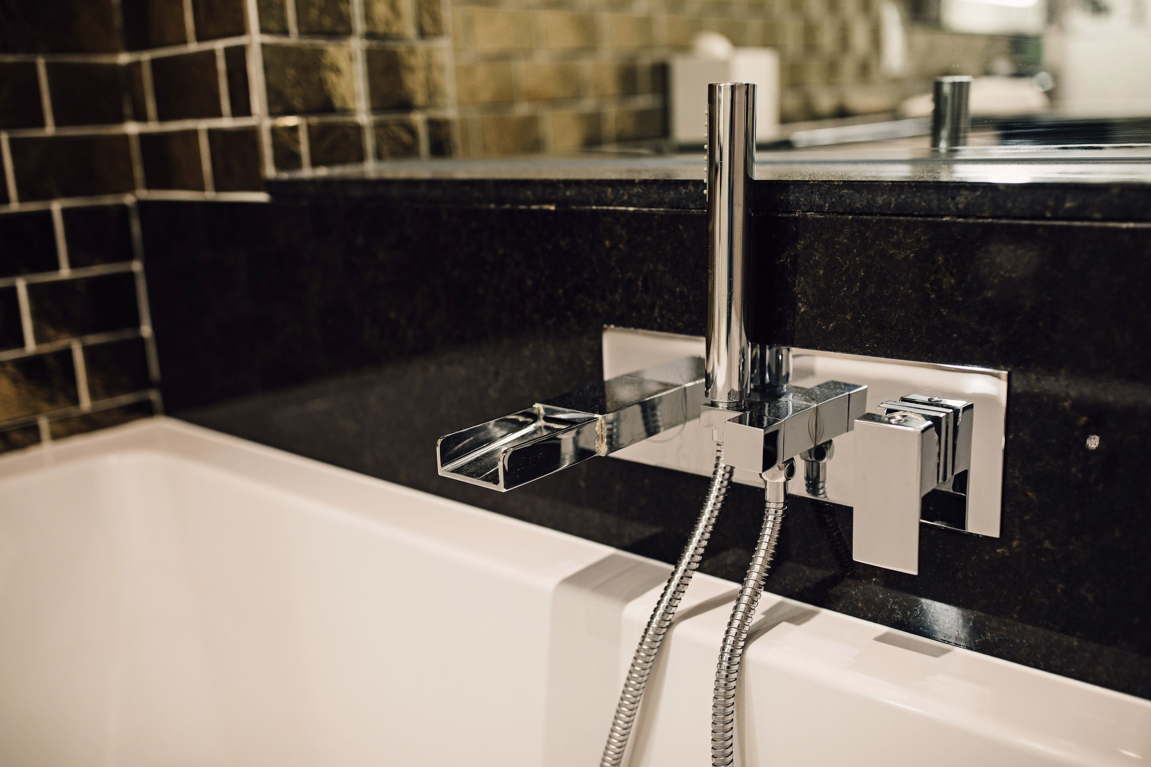 Une salle de bain moderne avec un robinet chromé, une douchette et un porte-serviettes.