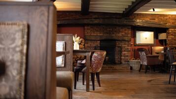 A cozy interior with a brick fireplace, wooden beams, and comfortable seating.
