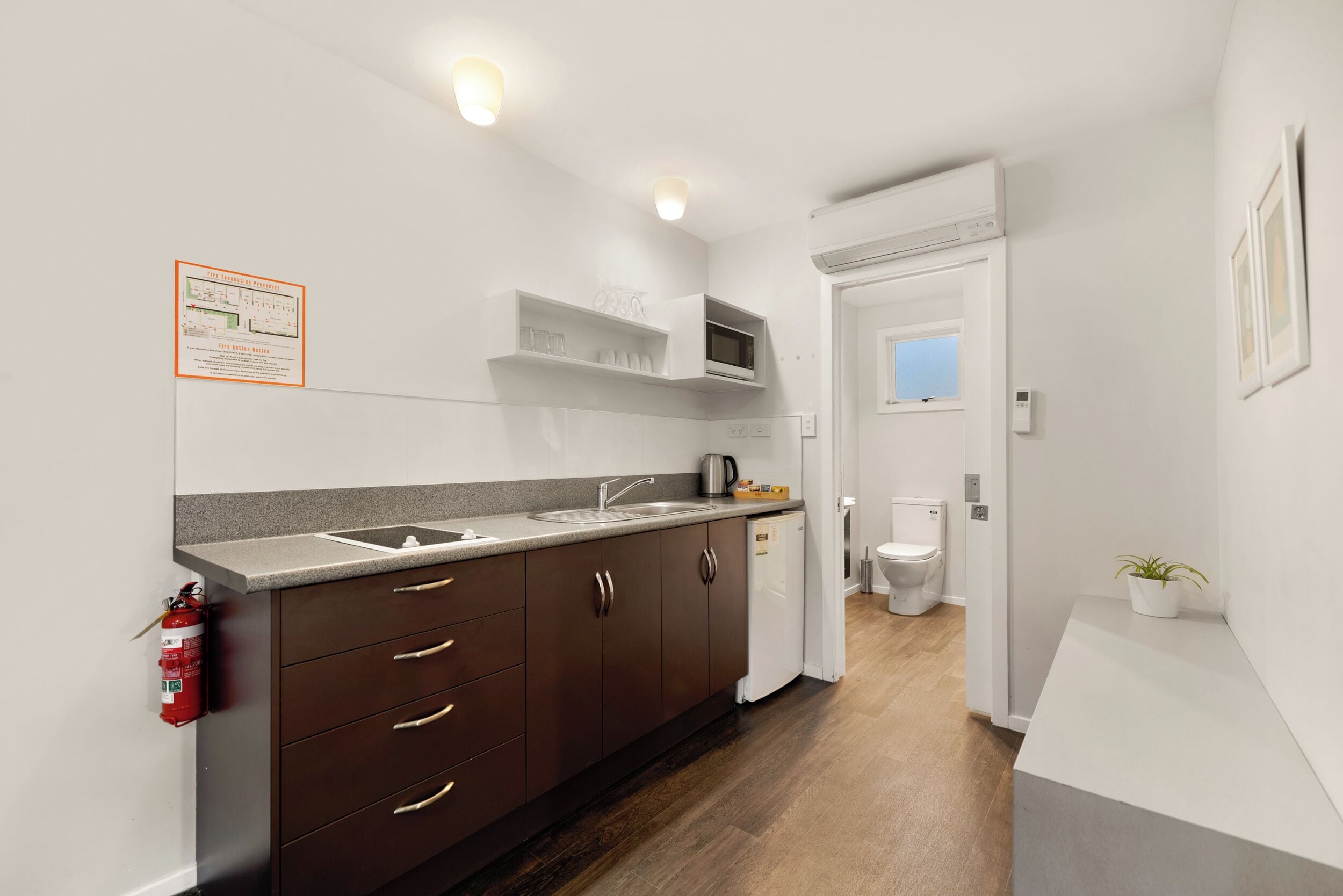 A modern kitchen with dark brown cabinets, a built-in microwave, and a stainless steel sink.