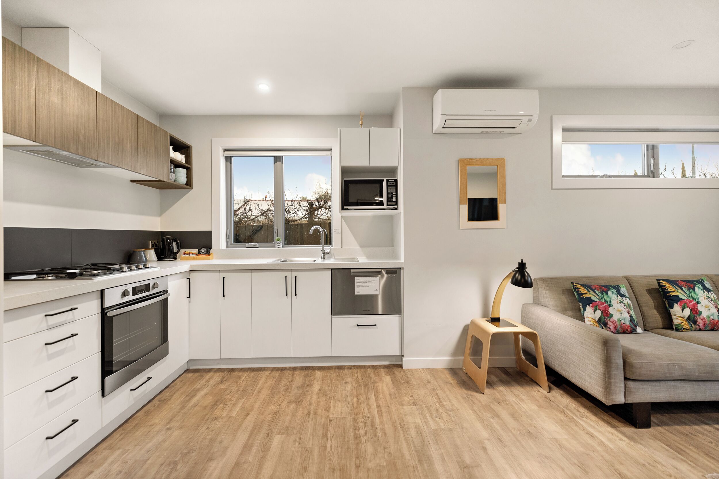 Una cocina moderna con armarios blancos, electrodomésticos de acero inoxidable y encimera de madera.