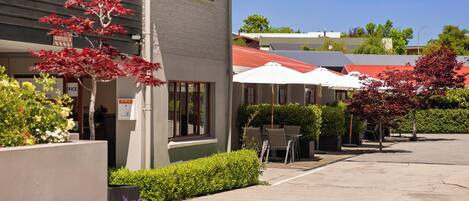 A building with a red roof, outdoor seating, and a sign indicating a business on the ground floor.