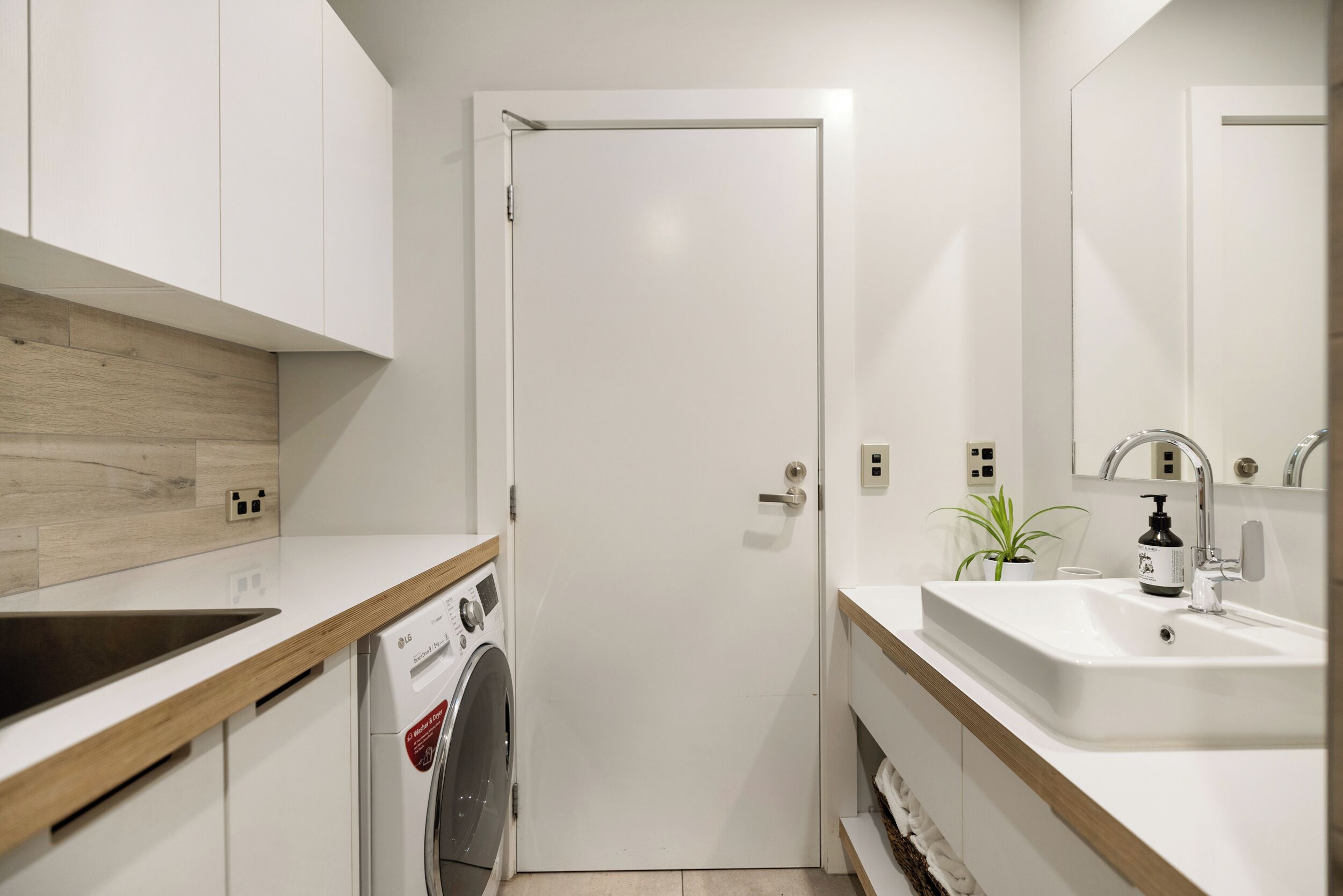 A compact kitchen with a washing machine, a sink, and a door.