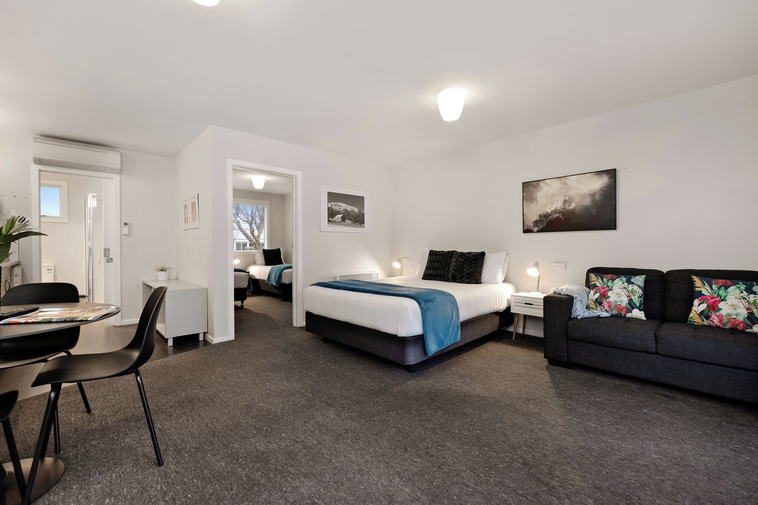 Una habitación de hotel moderna con una cama, un escritorio, un sofá y una mesa de comedor.