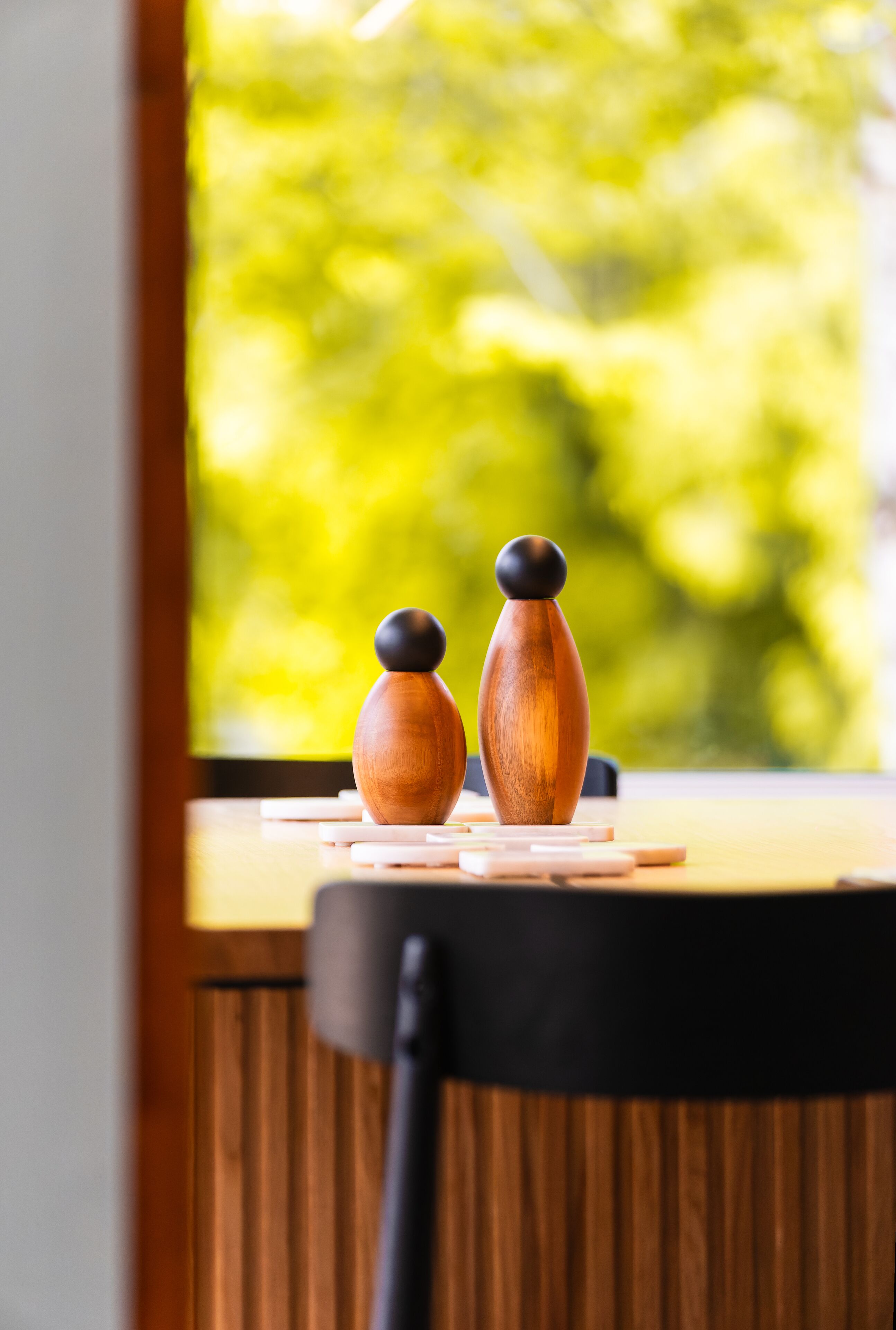 A wooden table with two wooden objects on it, a window with a blurred green background.