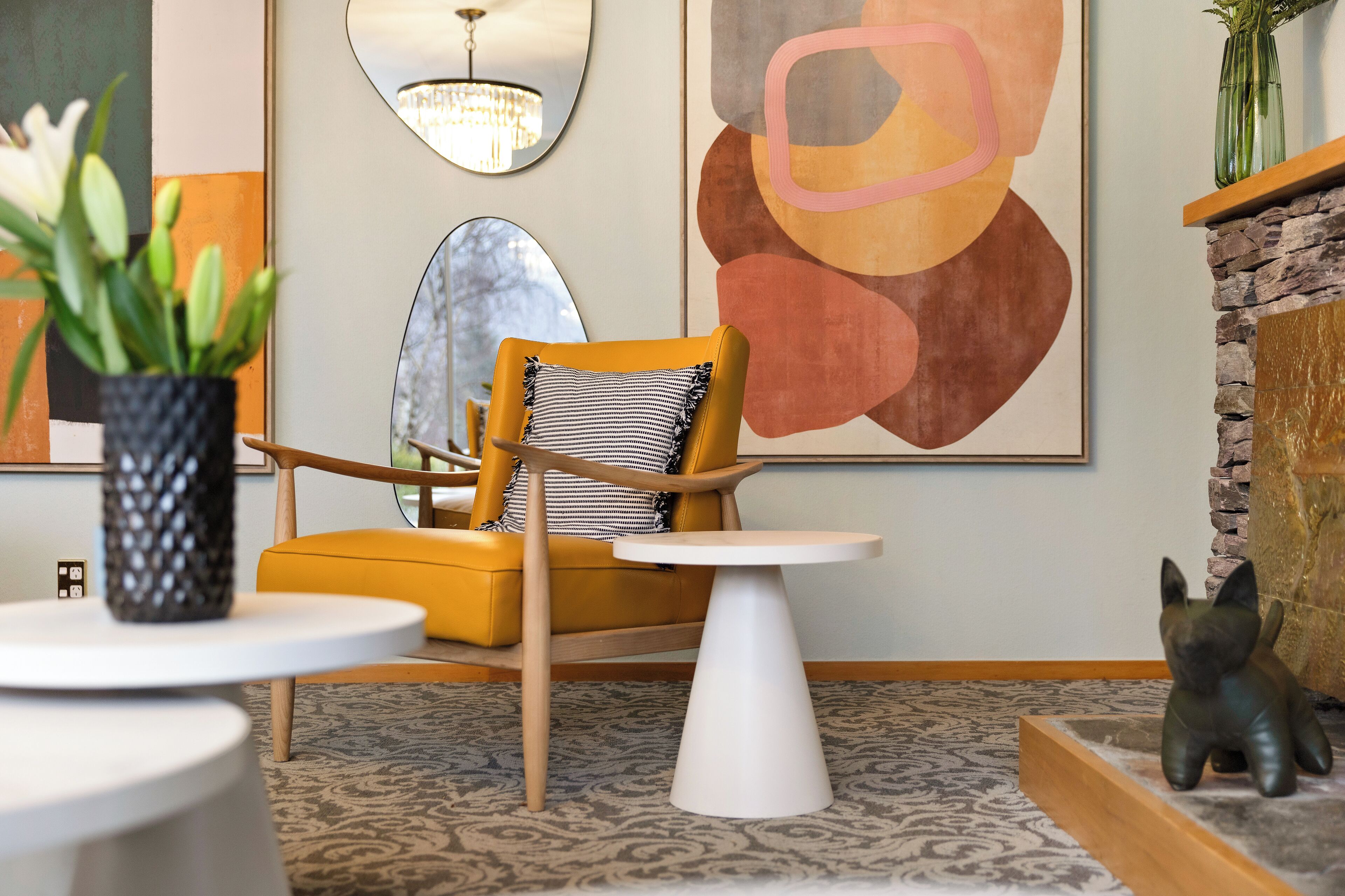 Un salon moderne avec un fauteuil jaune, une table ronde blanche et une cheminée décorative.