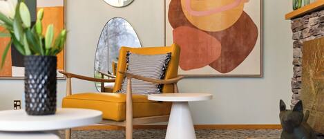 A modern living room with a yellow armchair, a white round table, and a decorative fireplace.