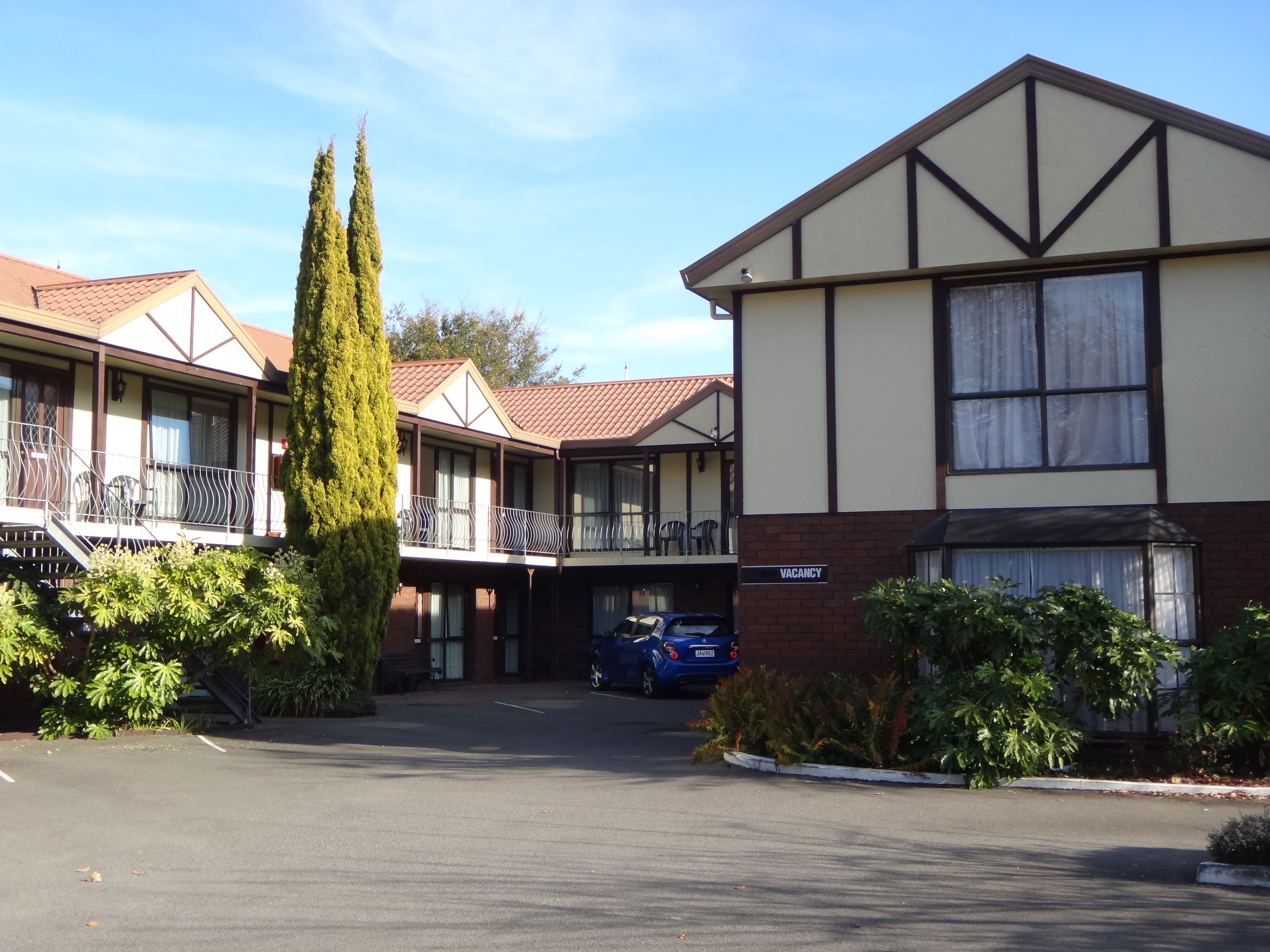 A motel with multiple units, a parking area, and a blue car parked in front.