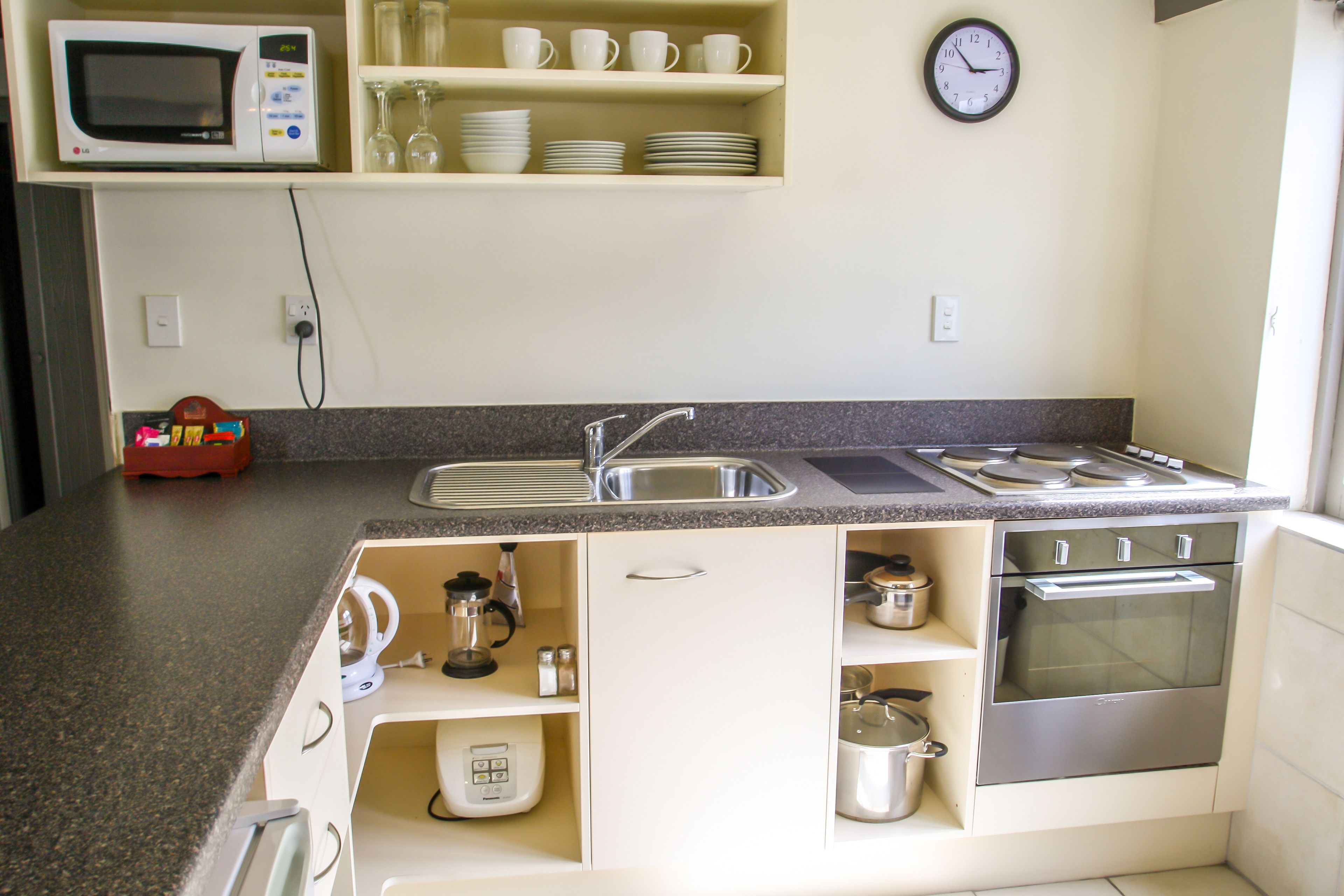 A compact kitchen with a microwave, sink, stove, and various appliances.