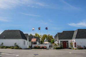 Un bâtiment avec une porte rouge, une clôture blanche et un ciel bleu clair.