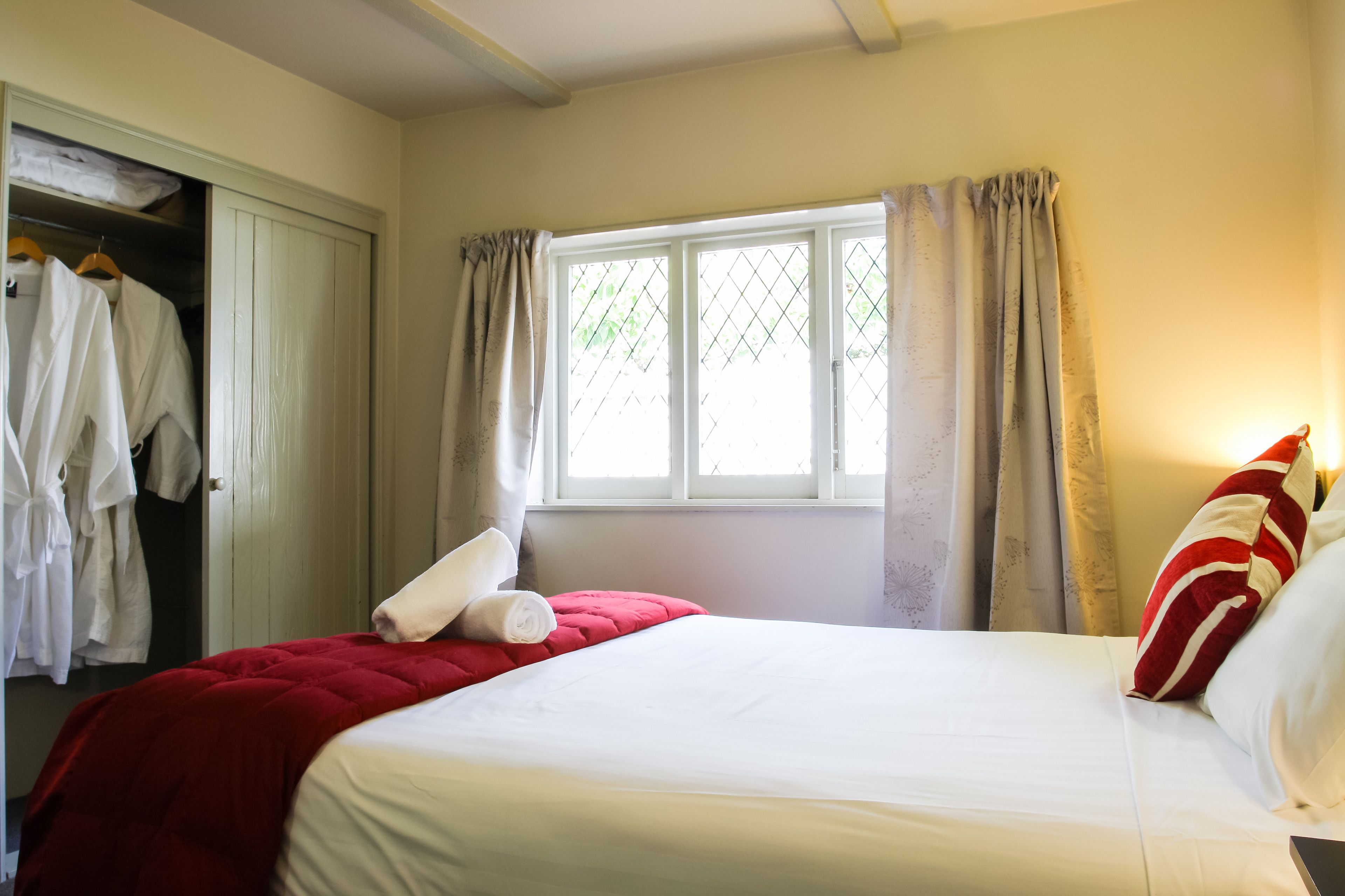 A hotel room with a bed, a wardrobe, and a window with curtains.