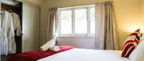 A hotel room with a bed, a wardrobe, and a window with curtains.