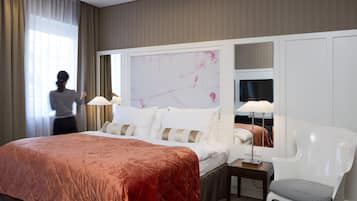 A hotel room with a large bed, a bedside table with a lamp, a chair, and a mirror.