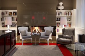 Una sala de estar moderna con chimenea, dos sillones, un sofá y una mesa de centro de vidrio.
