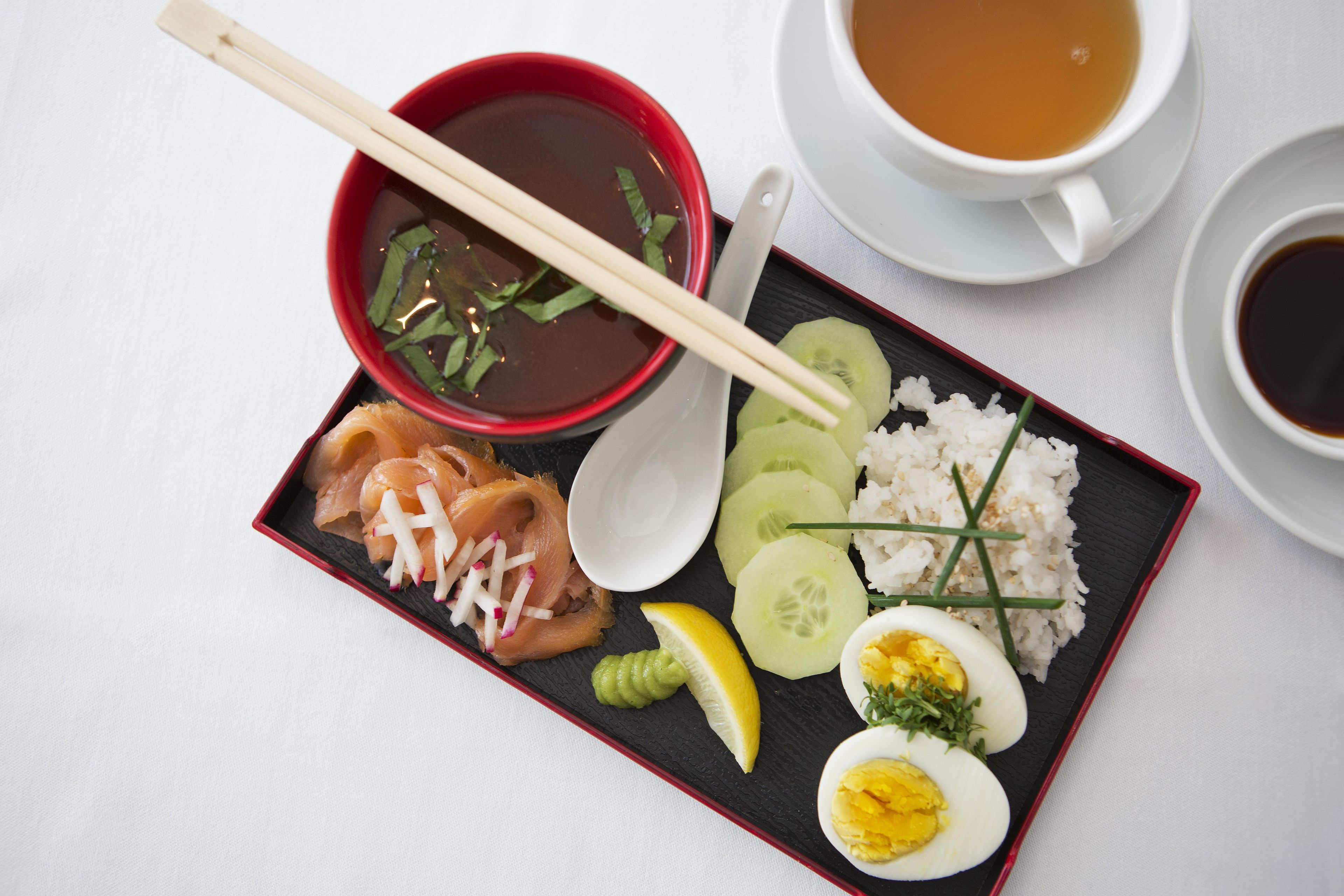 A meal with salmon, rice, cucumber, and a boiled egg on a black plate.