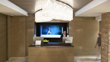 A modern reception area with a large flat-screen TV, a bowl of apples, and a laptop on a desk.
