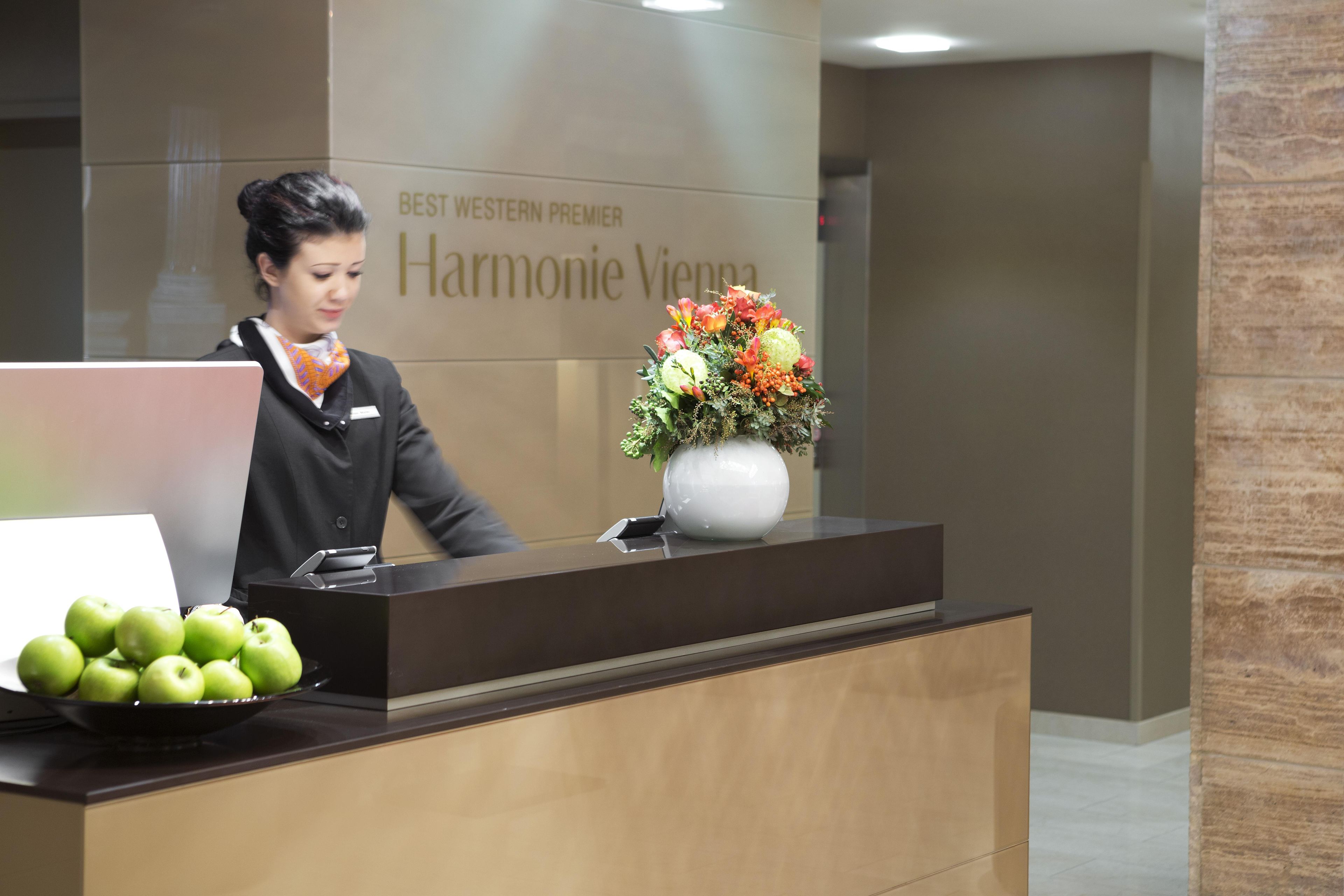 A reception desk with a nameplate, a vase of flowers, and a bowl of apples.