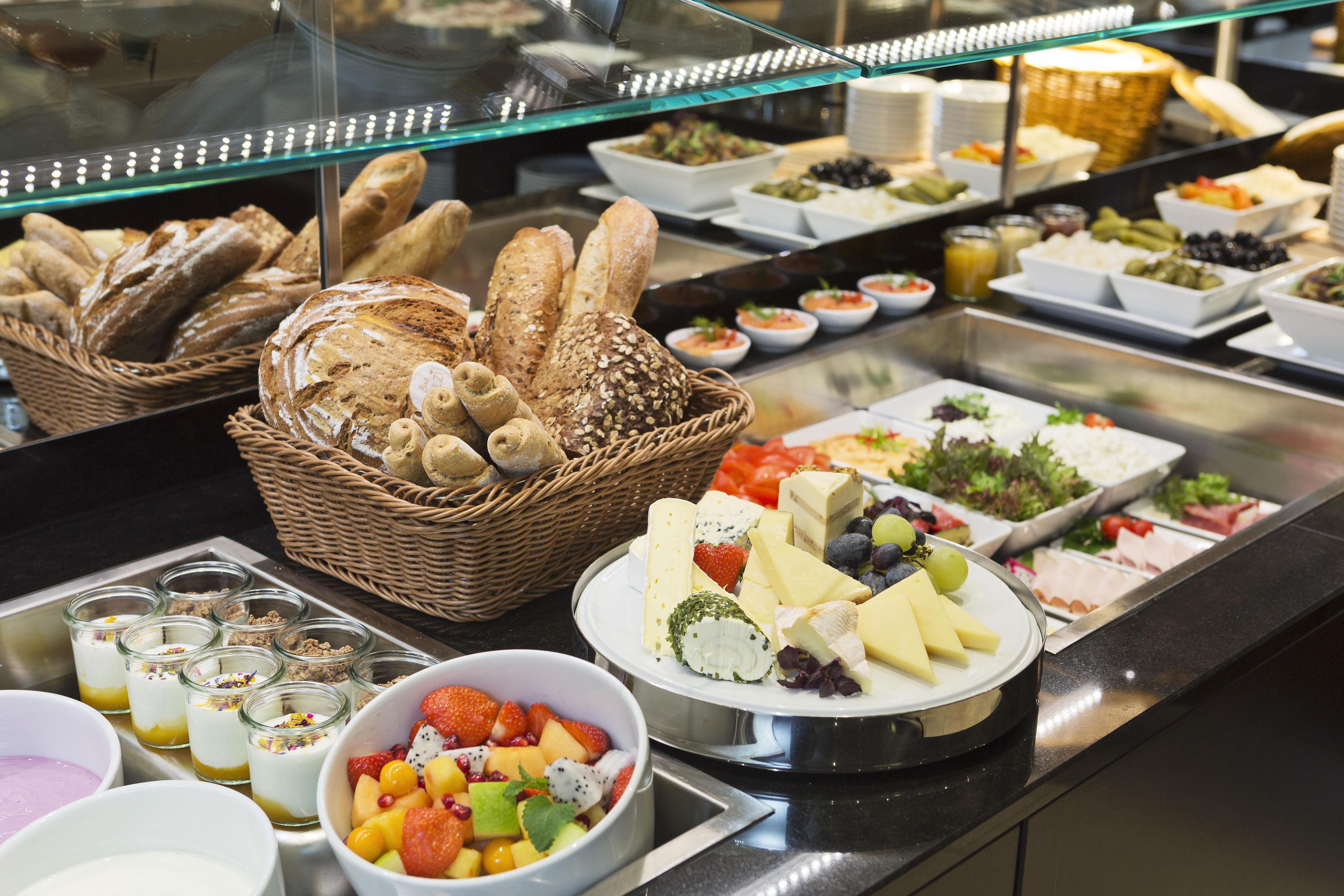 Un bufé con diferentes opciones de comida, incluyendo pan, queso, frutas y ensaladas.