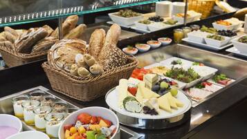 Un bufé con diferentes opciones de comida, incluyendo pan, queso, frutas y ensaladas.