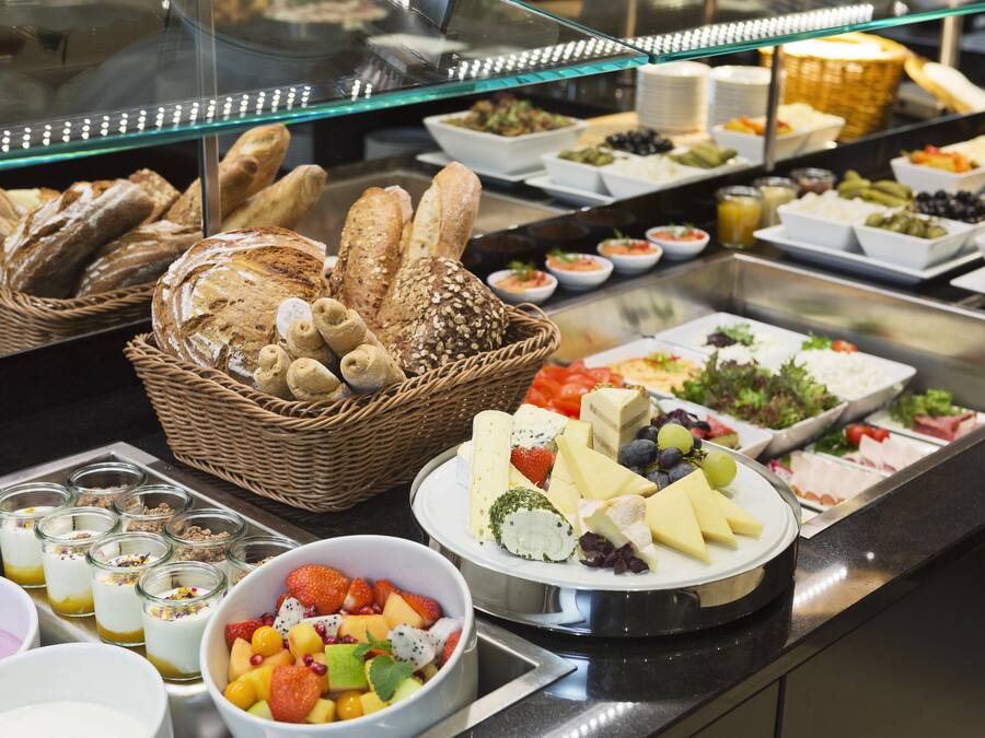 A buffet with various food items including bread, cheese, fruits, and salads.