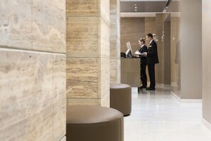 Un moderno vestíbulo de hotel con una recepción, una zona de estar y un pasillo que conduce a otras áreas del hotel.